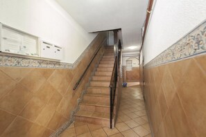 A staircase with a handrail, tiled walls, and a bulletin board with notices. - Gran Vía VI (Madrid)