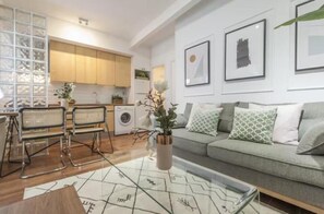 A modern living room with a sofa, a coffee table, and a dining area with chairs. - Gran Vía VI (Madrid)