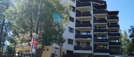 A multi-story residential building with balconies, a street lamp, and a parked car.