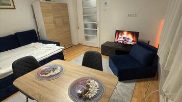 Ett kompakt bostadsutrymme med ett matbord, en soffa, en TV och en garderob.