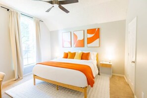 A bedroom with a bed, a ceiling fan, a nightstand, and a window with curtains. - Stay at Golden Hour | Pool + Hot Tub | Sleeps 10+ (Irving)