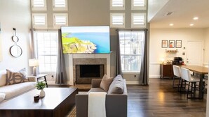 Un salon spacieux avec une cheminée, un téléviseur et un coin repas.