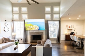 A spacious living room with a fireplace, a television, and a dining area. - Stay at Golden Hour | Pool + Hot Tub | Sleeps 10+ (Irving)