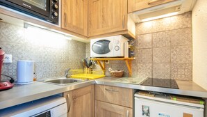 Eine Küche mit Holzausstattung, einer Mikrowelle, einem Geschirrspüler und einem Kühlschrank.