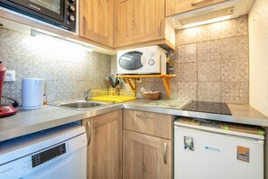 Eine Küche mit Holzausstattung, einer Mikrowelle, einem Geschirrspüler und einem Kühlschrank.