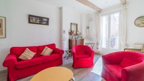 Un salón con un sofá rojo, una mesa de centro de madera y un sillón rojo.