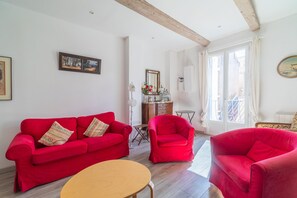 Ein Wohnzimmer mit einem roten Sofa, einem Holztisch und einem roten Sessel.