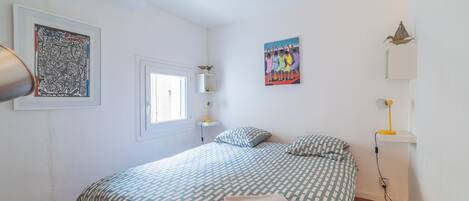 Un dormitorio con cama, ventilador de techo, obra de arte y ventana.