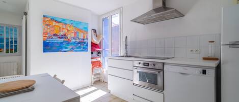 A modern kitchen with white cabinets, a Bosch dishwasher, an oven, and a stainless steel range hood.