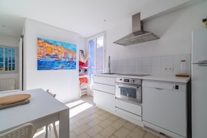 Eine moderne Küche mit weißen Schränken, einem Geschirrspüler von Bosch, einem Backofen und einer Edelstahl-Dunstesse.