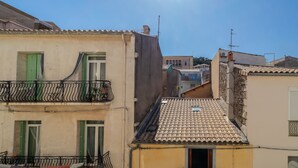 Un edificio con tejado de tejas, balcones con barandillas de metal y cielo despejado.