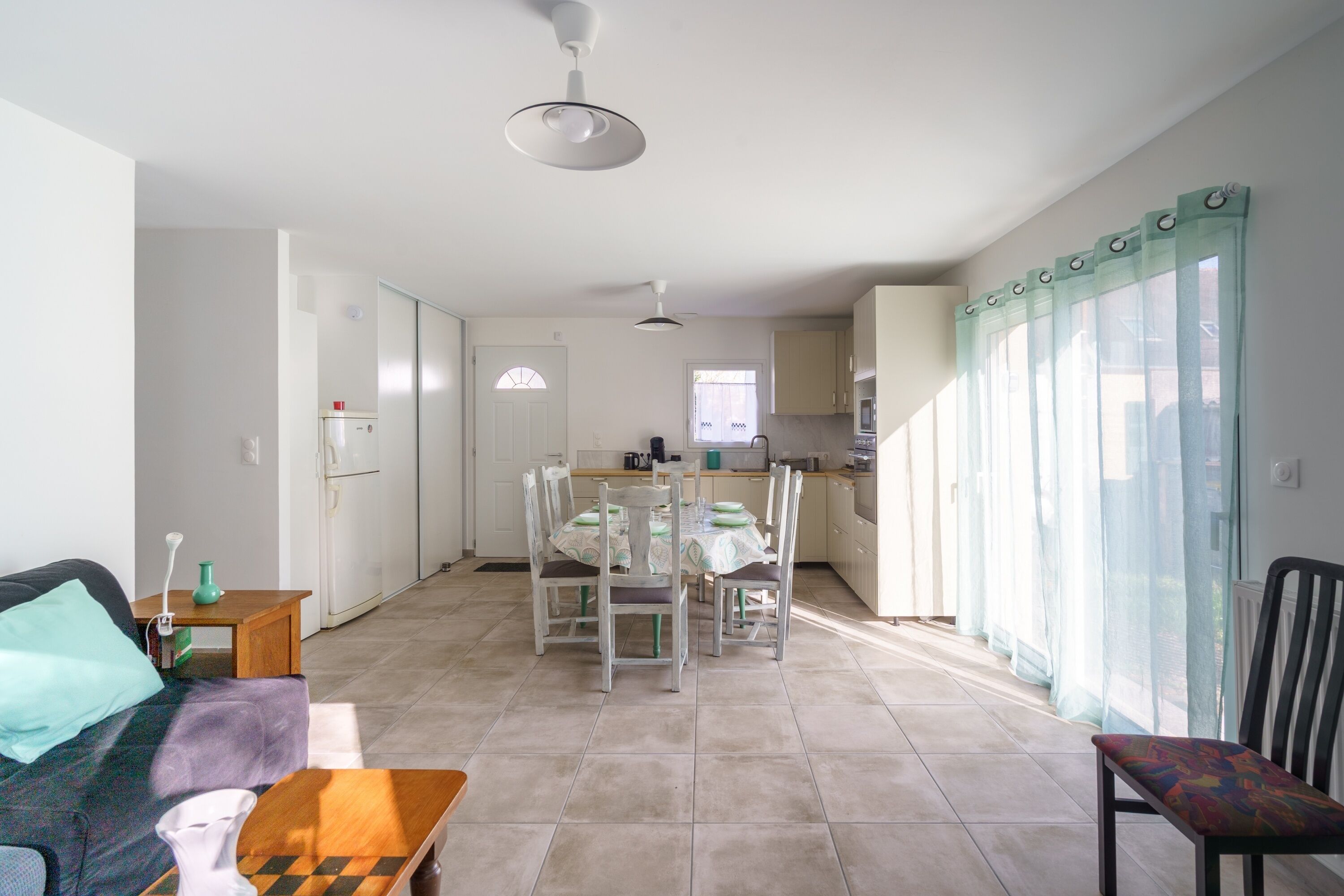 A modern kitchen with white cabinets, a dining area with a table and chairs, and a living area with a sofa and a coffee table.