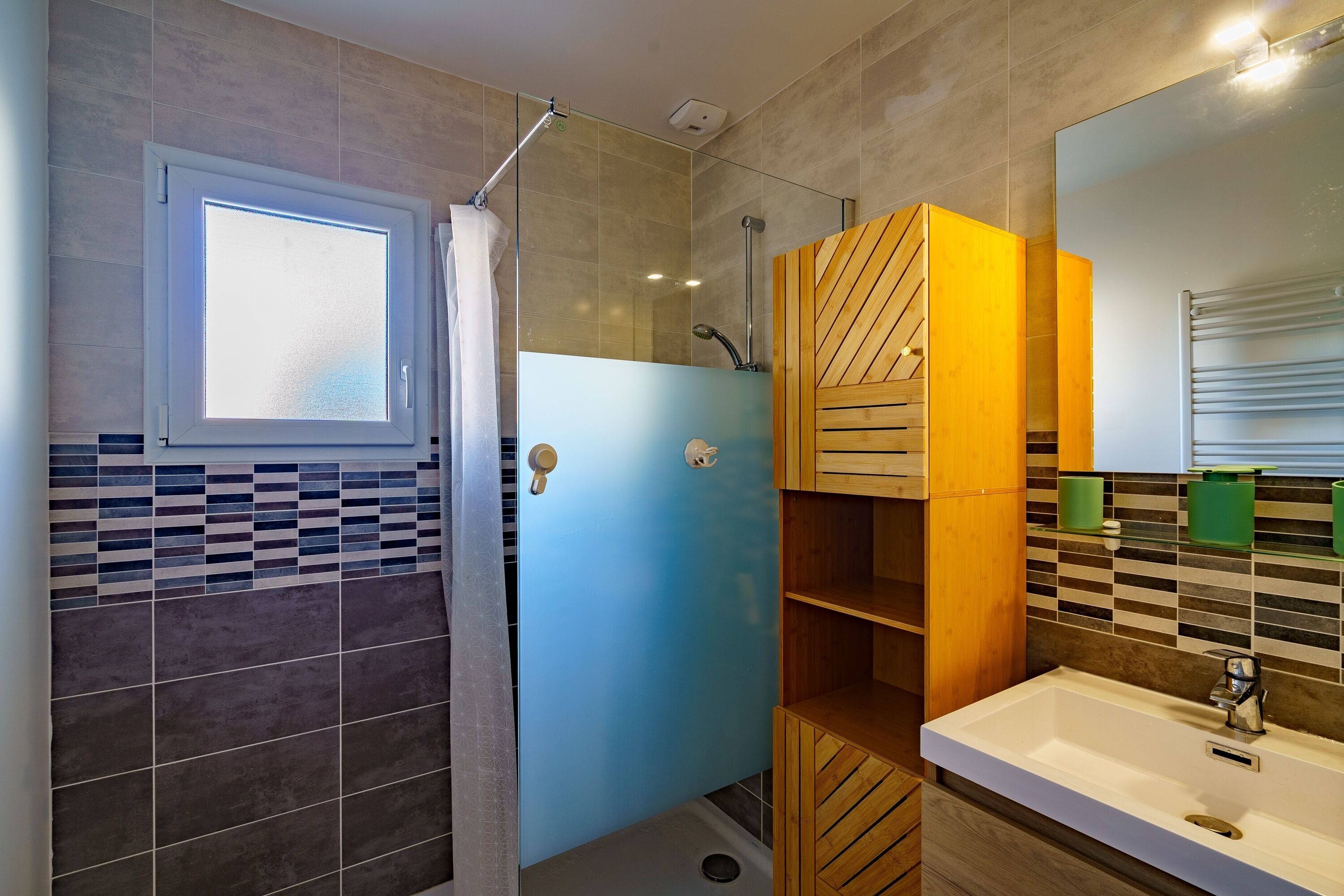 A bathroom with a shower, a sink, and a mirror.