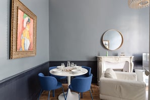 A dining area with a round table, blue chairs, and a white sofa.