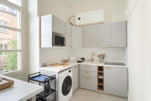 A compact kitchen with a washing machine, microwave, and a sink.
