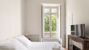 A hotel room with a bed, a television, and a window with a view of greenery. - Modjesko - Au coeur de Rennes (Rennes)