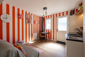 Une pièce avec des murs à rayures, un lit, une table avec des chaises, une fenêtre et une porte.