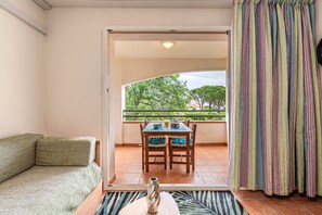 A balcony with a table and chairs, a sofa, and a view of trees and buildings. - L'Escapade Corse - À 80 mètres de la plage (San-Nicolao)