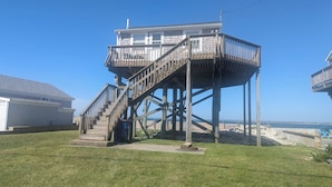 A wooden structure with a staircase, a small deck, and a view of the beach.
