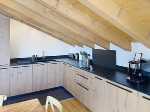 Eine moderne Küche mit Holzschränken, einer schwarzen Arbeitsplatte und einer Kaffeemaschine.