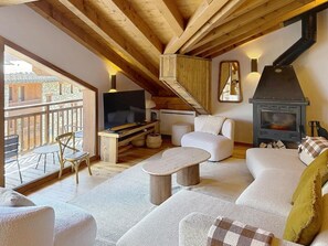 Ein gemütliches Wohnzimmer mit Sofa, Couchtisch, Fernseher und Kamin.