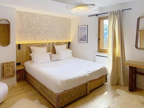 A bedroom with a wooden bed, a nightstand, a mirror, a window with curtains, and a wooden headboard. - 300m from ski slopes, balcony, fireplace or stove, parking, ski locker, 143m², La Rosière (Montvalezan)