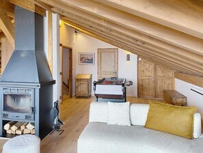 A loft bedroom with a wood-burning stove, a sofa, a futsal table, and wooden doors. - 300m from ski slopes, balcony, fireplace or stove, parking, ski locker, 143m², La Rosière (Montvalezan)