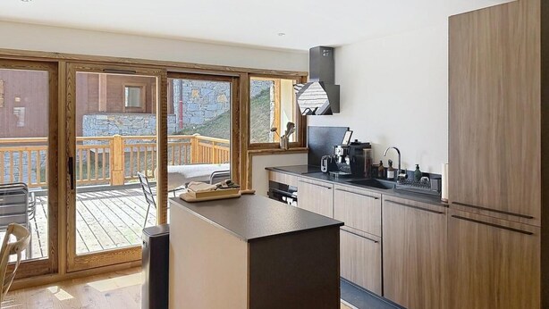 A modern kitchen with a central island, wooden cabinets, and a view of a wooden deck. - 300m from ski slopes, terrace, parking, ski locker, 162m², La Rosière (Montvalezan)