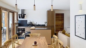 A modern kitchen with wooden cabinetry, a dining table with chairs, and a view of the outdoors. - 300m from ski slopes, terrace, parking, ski locker, 162m², La Rosière (Montvalezan)