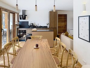 A modern kitchen with wooden cabinetry, a dining table with chairs, and a view of the outdoors. - 300m from ski slopes, terrace, parking, ski locker, 162m², La Rosière (Montvalezan)