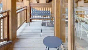 Eine Holzdielen-Terrasse mit Glasgeländer, einem Tisch und Stühlen.