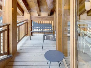 Eine Holzdielen-Terrasse mit Glasgeländer, einem Tisch und Stühlen.