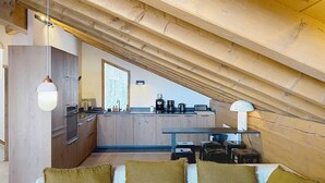 Ein Loft-Zimmer mit Küchenbereich, einer Couch mit Kissen und einer Pendelleuchte.