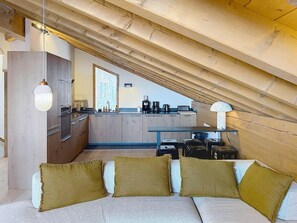 Ein Loft-Zimmer mit Küchenbereich, einer Couch mit Kissen und einer Pendelleuchte.