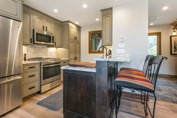 A modern kitchen with stainless steel appliances, a central island, and dark wood cabinetry.