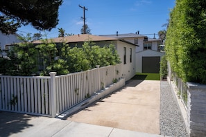 A residential property with a paved driveway, a white picket fence, and a well-maintained lawn. - BRAND NEW - Single-Family Solana Beach House, Steps from the Beach. (Solana Beach)