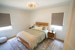 A bedroom with a bed, nightstands, a lamp, a window with a blind, and a rug. - BRAND NEW - Single-Family Solana Beach House, Steps from the Beach. (Solana Beach)