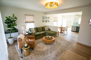 A living room with a sofa, coffee table, lamp, and a potted plant.