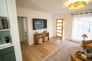 A living room with a flat-screen TV, a wooden console table with baskets, a patterned rug, and a sofa with a lamp. - BRAND NEW - Single-Family Solana Beach House, Steps from the Beach. (Solana Beach)