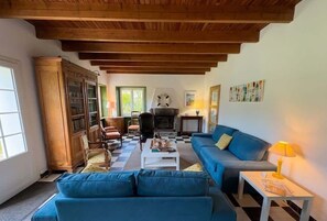 Un saló amb un sofà blau, una taula de cafè blanca i una llar de foc.