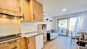 Una cocina moderna con armarios de madera, lavavajillas integrado y una zona de comedor con mesa y sillas.