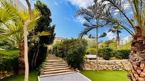 Un sendero que conduce a un edificio con un muro de piedra y abundante vegetación.