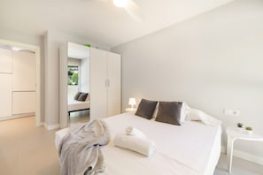Habitació d'hotel moderna amb un llit gran, una taula de nit, un escriptori petit i un armari.