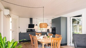 A modern kitchen with white cabinets, a black countertop, and a dining area with wooden chairs and a table. - 4 Star Holiday Home in Ansager (Ansager)