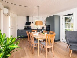 A modern kitchen with white cabinets, a black countertop, and a dining area with wooden chairs and a table.