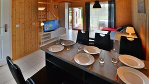 Un intérieur en bois comprenant une table à manger pour quatre personnes, un téléviseur et un canapé.