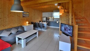 Un intérieur en bois comprenant un canapé, une table à manger, un téléviseur, une cuisine et un escalier.