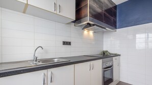 Eine moderne Küche mit weißen Schränken, einer Edelstahl-Spüle und einem eingebauten Backofen.
