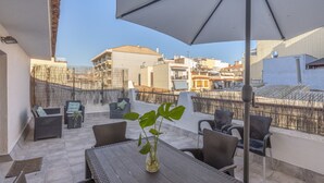 Eine Dachterrasse mit Sitzgelegenheiten im Freien, einem Tisch mit Pflanze und einem großen Sonnenschirm.