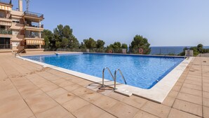 A swimming pool with a view of the sea, surrounded by a building with balconies. - SunAndBed Penthouse Faro – Spectacular Sea Views, Pool, Sports Court (Salou)